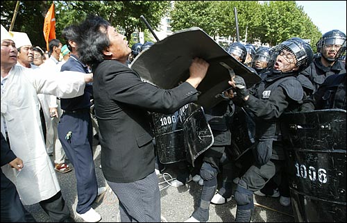 경찰이 운구차를 확보하기 위해 진입하는 과정에서 운구차 주변을 지키는 사람의 머리를 방패로 가격하고 있다. 